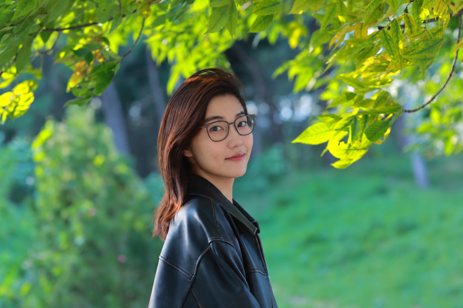 Portrait of Qingyang Wan outdoors beneath green leaves